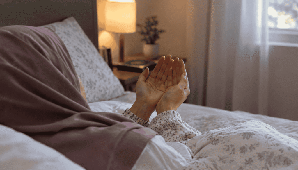 Person making dua while lying in bed with hands raised in prayer